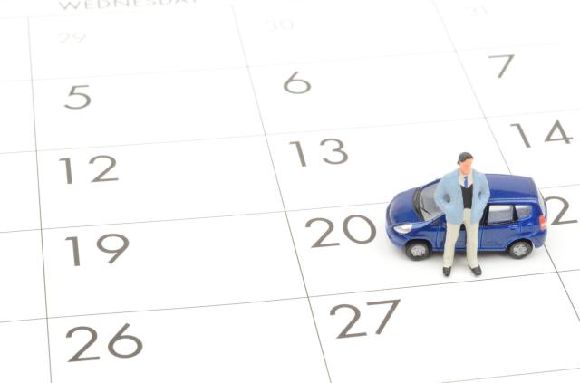 カレンダーの上に置かれたミニカーと人型のオブジェ