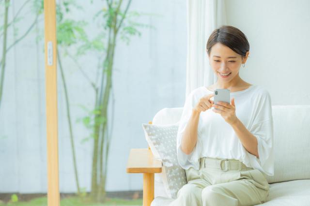 リビングでスマートフォンを操作する女性