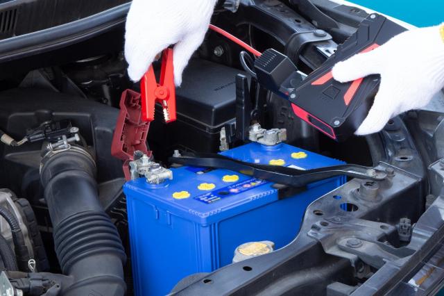 ジャンプスターターを持つ整備士