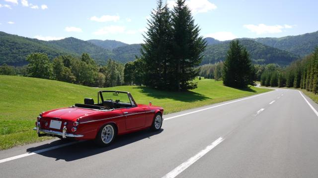 広大な自然を走る赤いクラシックカー