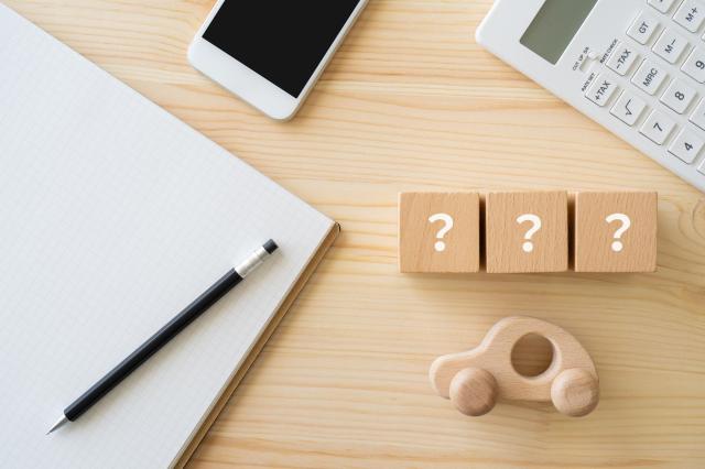 クエスチョンマークが書かれた積み木や木製の車と文房具