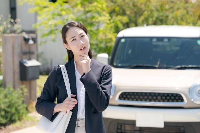 車の前で考える女性