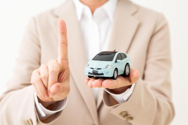 ミニカーを持って人差し指を立てる女性