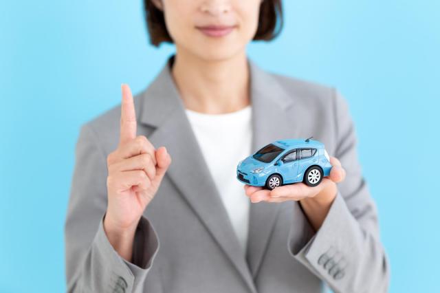ミニカーを手に注意を促す女性